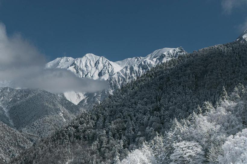 Snow-covered mountains under a clear blue sky in the Takayama region of Japan during winter